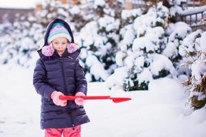 Little girl playing with red shovel in the garden photo