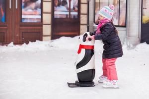 Adorable niña feliz disfrutando de patinar en la pista de hielo foto