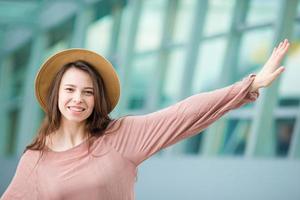 Portrait of young woman an airport lounge waiting for boarding. Happy girl in hat in international airport photo