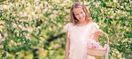 Adorable little girl in blooming apple garden on beautiful spring day photo