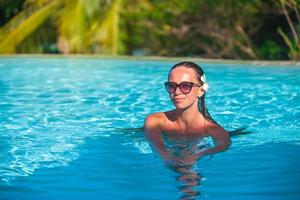Young beautiful woman enjoying luxury quiet swimming pool photo