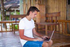 Closeup young man using tablet computer on exotic resort photo