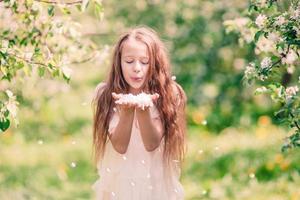 Adorable little girl in blooming apple garden on beautiful spring day photo