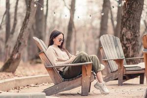 mujer caucásica con celular al aire libre en la cafetería. chica con teléfono inteligente móvil. foto