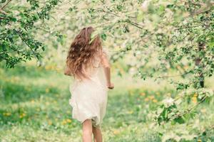 Adorable little girl in blooming apple garden on beautiful spring day photo