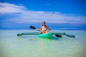 mujer joven en kayak solo en el mar azul claro foto