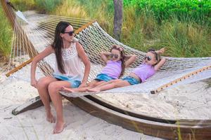 mamá y niñas relajándose en una hamaca en un resort tropical foto