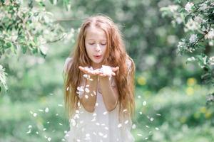 Adorable little girl in blooming apple garden on beautiful spring day photo