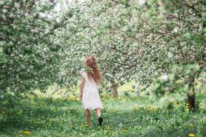 adorable niñita en un floreciente jardín de manzanas en un hermoso día de primavera foto