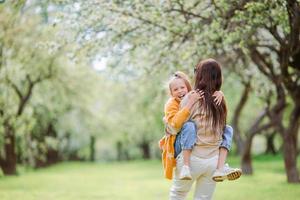 Family of mother and daughter in blooming cherry garden photo