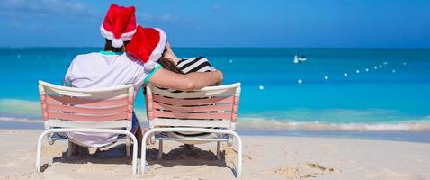 Young romantic couple in Santa hats during beach vacation photo