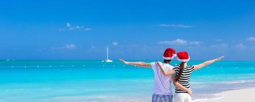 joven pareja romántica con sombreros de santa durante las vacaciones en la playa foto