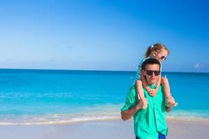 adorable niña diviértete con papá durante la playa tropical foto