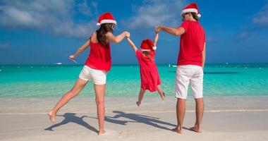 familia feliz de tres en sombreros de navidad durante vacaciones tropicales foto