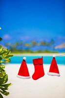 Red Santa hats and Christmas stocking hanging on tropical beach photo