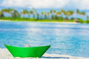 Colorful paper boat on tropical white beach outdoors photo