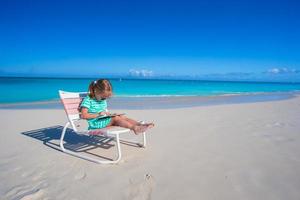 Little girl with laptop on beach during summer vacation photo