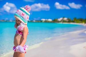 Little adorable girl in warm knitted hat and mittens on beach photo