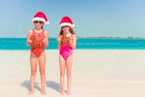 Adorable little girls on Christmas holidays on the beach photo