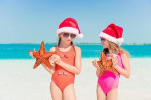 Adorable little girls on Christmas holidays on the beach photo