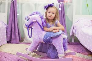 adorable niña con un caballo de juguete en casa foto