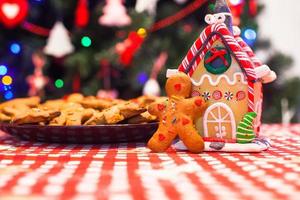 Cute gingerbread man in front of his candy ginger house background the Christmas tree lights photo