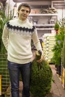 Young man choose Christmas tree in the market photo