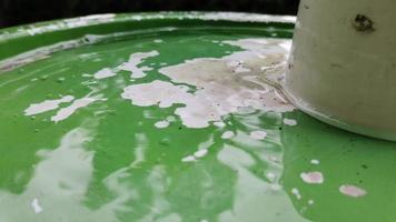 Slow motion of rainwater dripping over the bucket is green. video