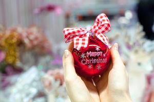 Beautiful red ball in hands of a young woman for Christmas photo