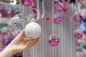 Woman holding white Christmas bauble at store photo