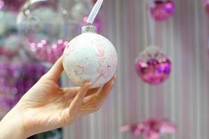 hermosa bola blanca en el árbol de navidad en la mano foto