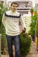 Young man choose Christmas tree in the market photo