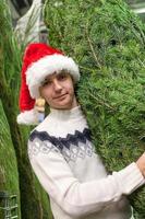 joven comprando un árbol de navidad en la tienda foto