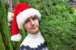 Young man buying a Christmas tree in the store photo