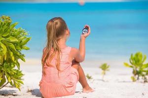 niña viajera con una brújula en la mano en la playa foto