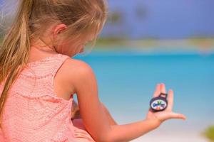 niña viajera con una brújula en la mano en la playa foto