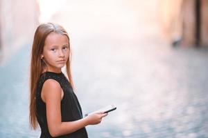 adorable niña con teléfono celular en la ciudad italiana durante las vacaciones de verano foto