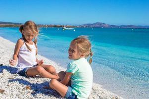 Adorable cute girls have fun on white beach during vacation photo