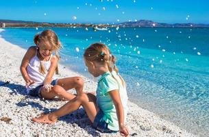 Adorable girls have fun on white beach during vacation photo