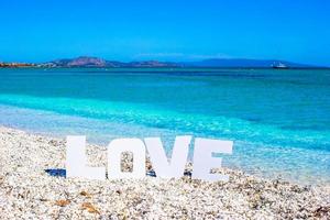 palabra amor sobre fondo de playa tropical de mar turquesa y cielo azul foto