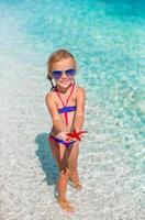 Little adorable girl with sea star at the tropical beach photo