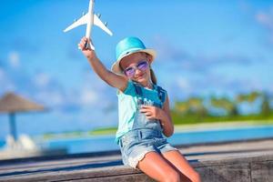 niña feliz con avión de juguete en las manos en la playa de arena blanca