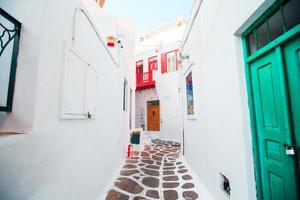 The narrow streets of greek island with white balconies, stairs and colorful doors. Beautiful architecture building exterior with cycladic style. photo