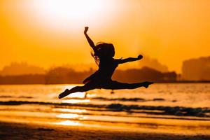 Adorable happy little girl on white beach at sunset. photo