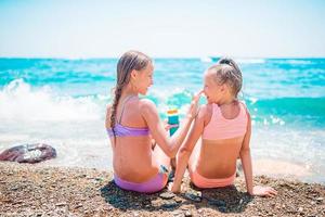 protección UV. hermana pone protector solar en la nariz de su hermana pequeña foto