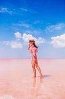 mujer con sombrero camina sobre un lago salado rosa en un día soleado de verano. foto