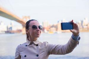 Young woman photographing herself on background of Brooklyn Bridge photo