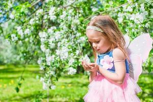 Adorable little girl in blossoming apple tree garden photo