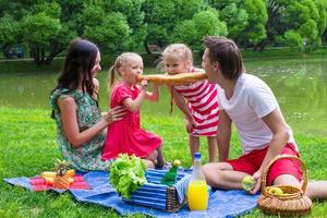 feliz familia joven de picnic al aire libre cerca del lago foto