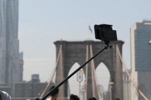 Selfie with smartphone and tripod on Brooklyn bridge on sunny day photo